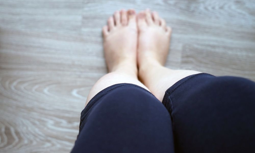  Pohľad na nohy zhora ukazuje mierny opuch členkov a priehlavku, čo poukazuje na opuch nôh spôsobený zadržiavaním vody, dlhým sedením alebo problémami s cirkuláciou.