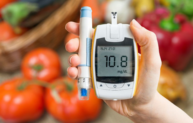 Glukomer s výsledkom hladiny cukru, obklopený zeleninou, symbolizuje diabetickú diétu.
