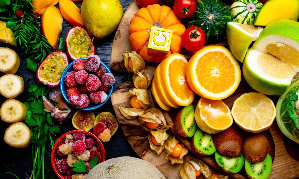  Pestrá kombinácia ovocia a zeleniny bohatých na vitamín C, ako citrusy, kiwi a bobuľové plody, znázorňuje prirodzené zdroje vitamínu C v každodennej strave.