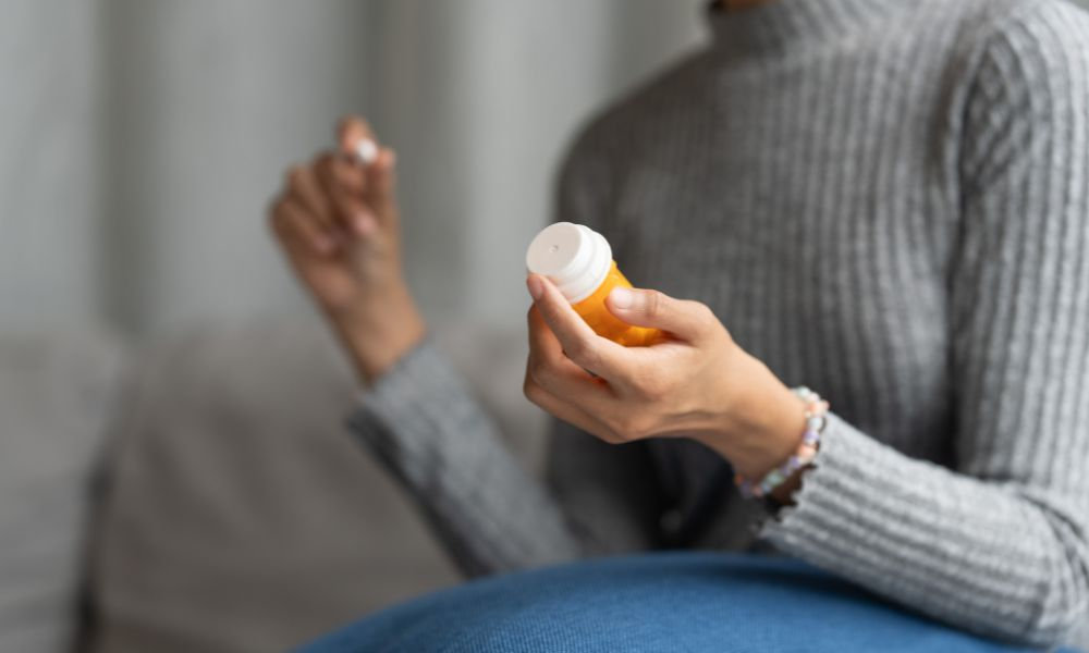  Žena drží liekovku s vitamínom C v domácom prostredí, čo symbolizuje pravidelné dopĺňanie vitamínu C na podporu imunity, prevenciu nachladnutia a celkové zdravie.