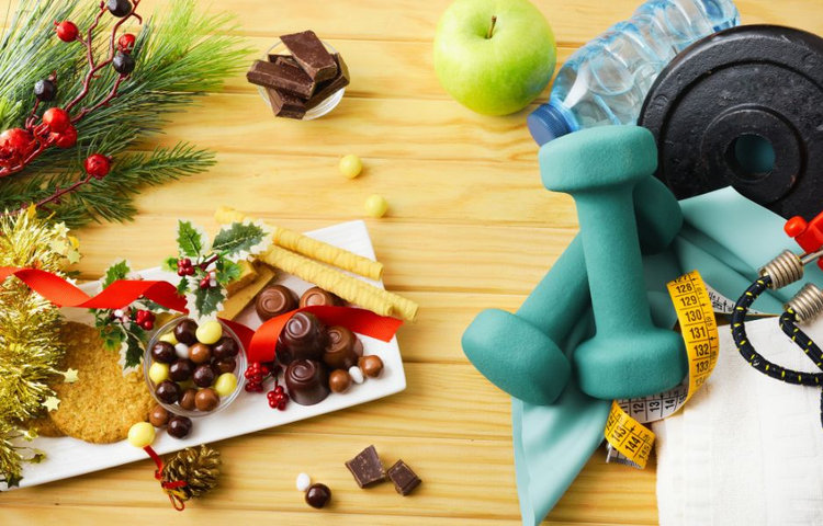Kombinácia fitnes vybavenia a vianočných sladkostí – balans medzi chudnutím a udržaním zdravia po sviatkoch.