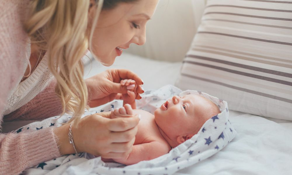 Matka komunikujúca so svojím bábätkom na posteli – šestonedelie a dôležitosť emocionálneho spojenia