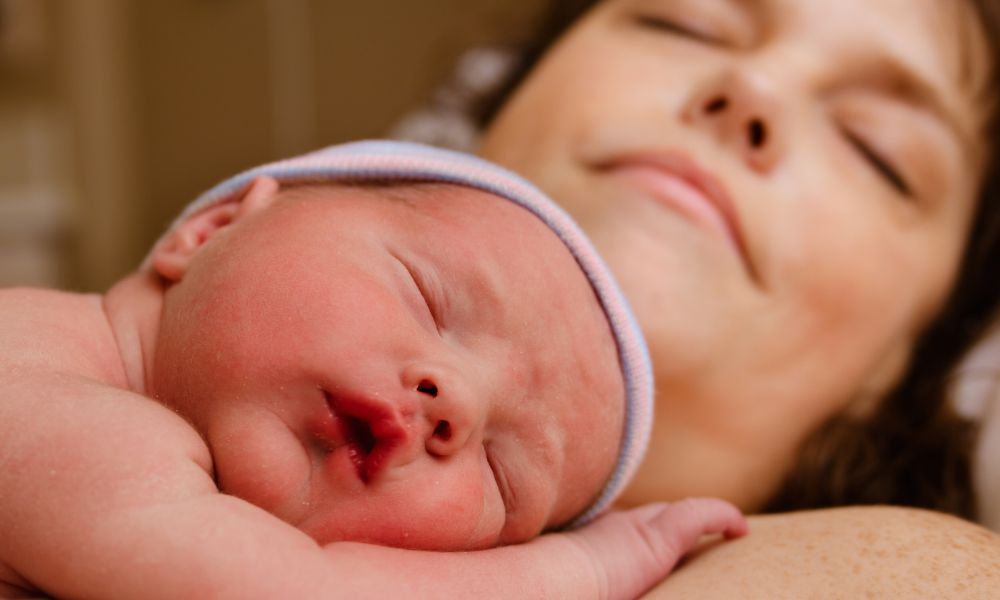  Novorodenec odpočíva na hrudi matky, ktorá sa zotavuje po pôrode. Obdobie po pôrode prináša zmeny ako uvoľnené brušné svaly, krvácanie z maternice, citlivá vagína a neskôr aj návrat menštruácie a možné problémy so sexom po pôrode.