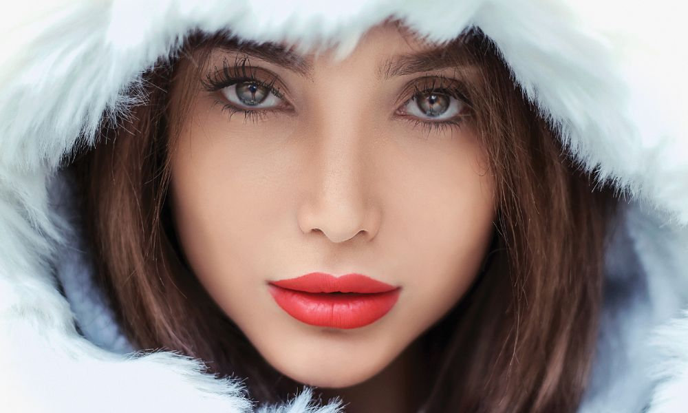  Detailný portrét ženy v kapucni s hustou kožušinou zvýrazňuje potrebu hydratácie pleti, ochranných krémov a zimnej starostlivosti proti vysušeniu či podráždeniu pokožky v decembri.