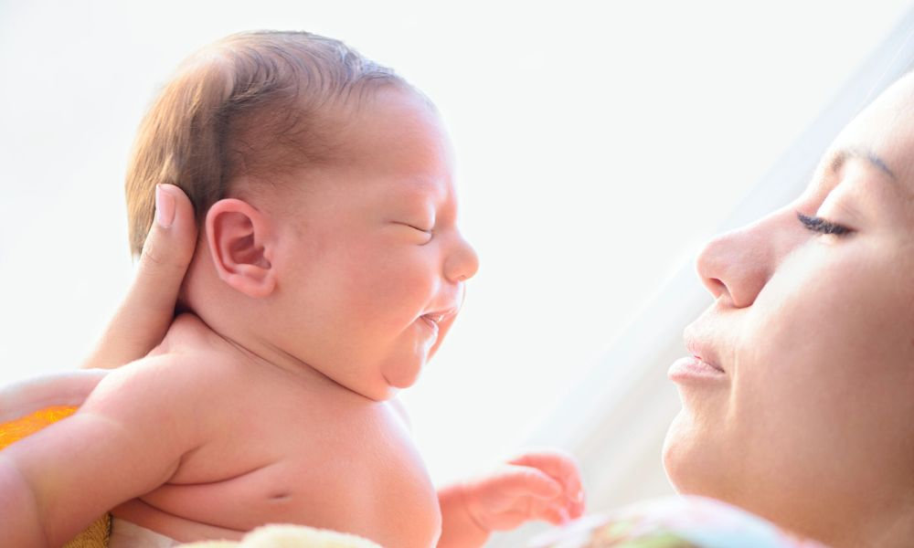  Matka drží svoje novonarodené dieťa, čo predstavuje prvé chvíle po pôrode plné lásky, ale aj fyzických zmien ako brucho po pôrode, krvácanie, bolestivá vagína a hormonálne výkyvy ovplyvňujúce menštruáciu a vypadávanie vlasov.